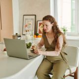 A pregnant woman working from home on a laptop.