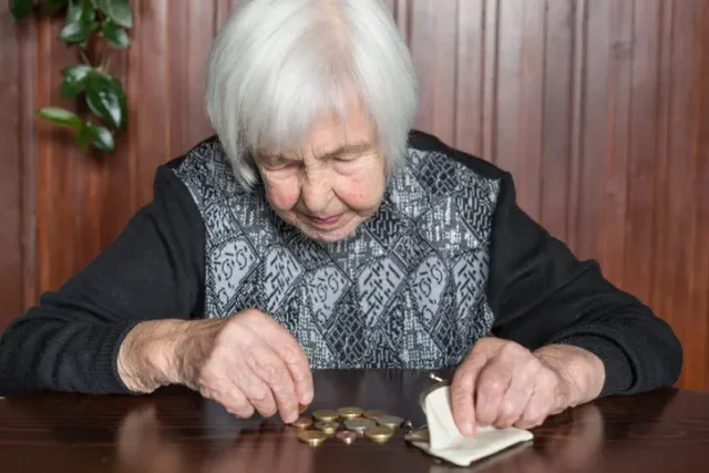 An old woman managing her expenses, counting coins in her wallet.
