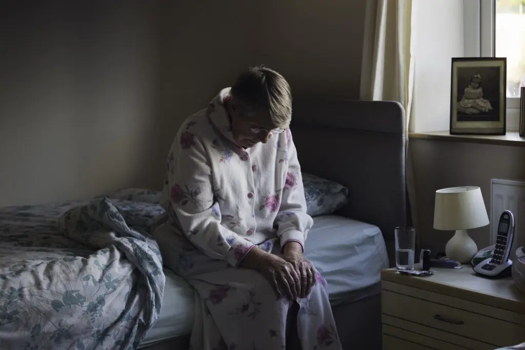 Old woman sitting on a bed suffering from nursing home abuse in North Carolina