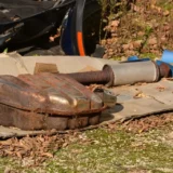 A used, rusted exhaust in the ground. Why do People Steal Catalytic Converters?
