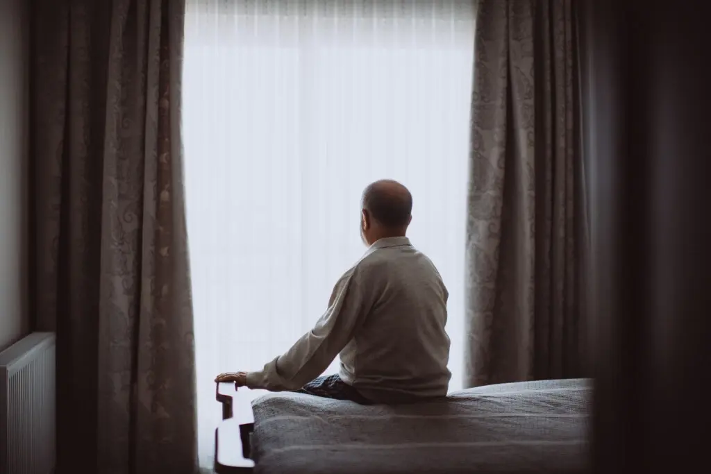 An old man looking out of a shining window, suffering nursing home abuse in Ohio.