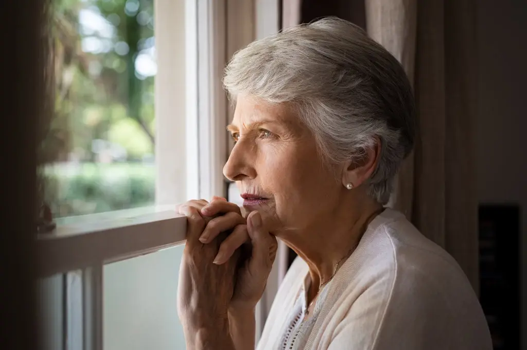Nursing home abuse in Virginia hurting a sad woman looking out of a window.