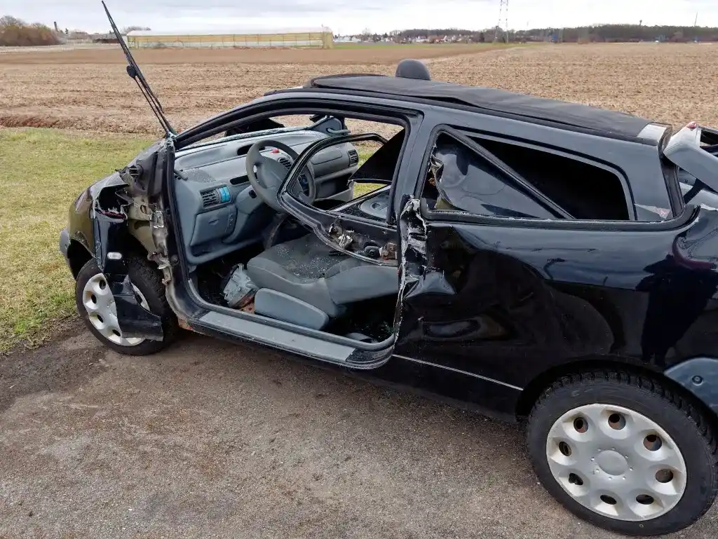 A destroyed black hatchback hit by a t-bone car accident.