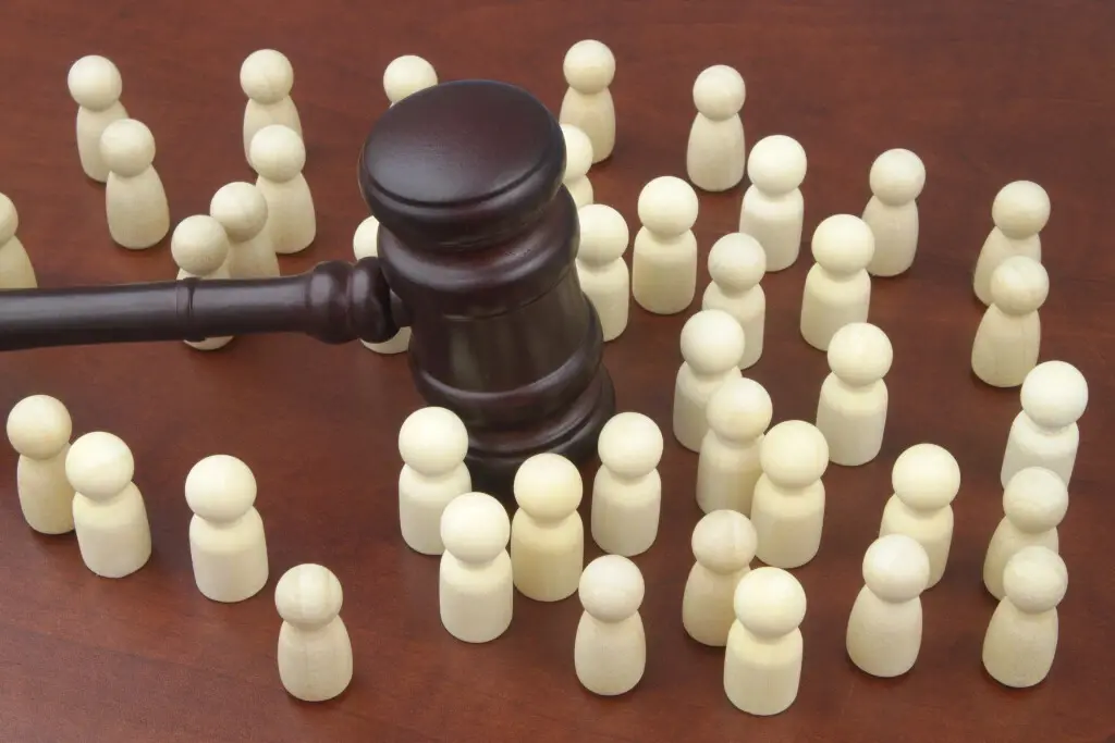 A gavel over a group of white dolls. What is a class action lawsuit?