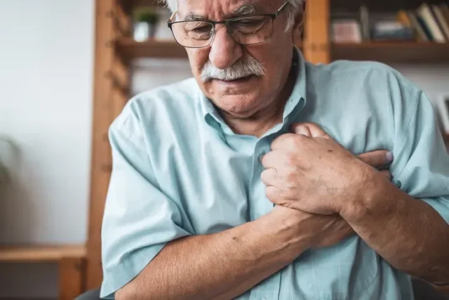 An old man grabbing his chest, suffering from nursing home physical abuse