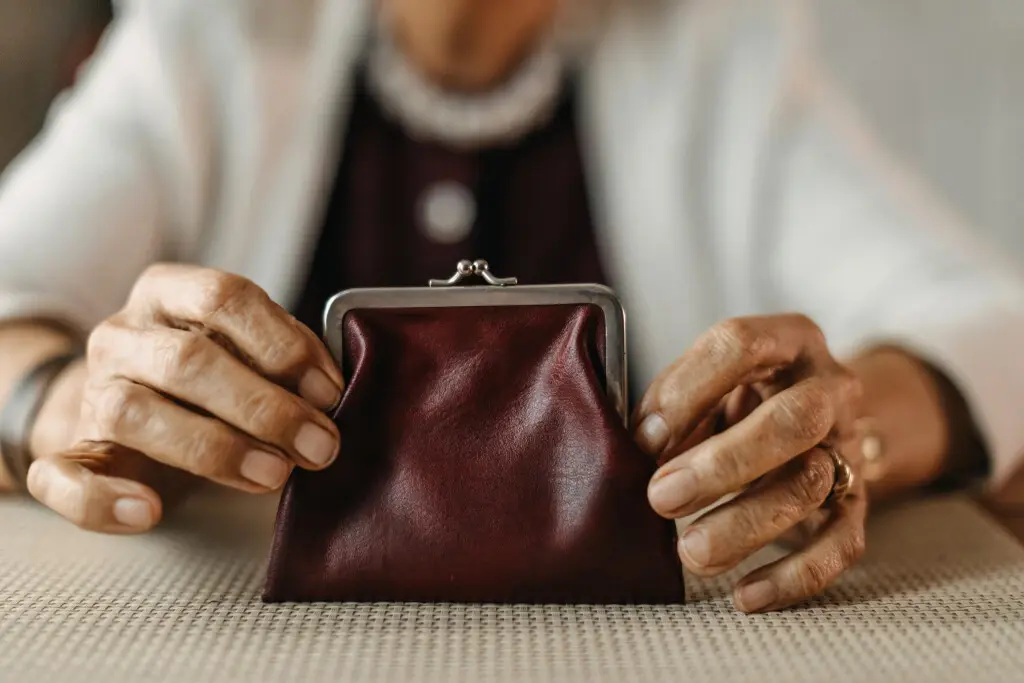 Do nursing homes take all your money? An elderly person holding a wallet on a table.
