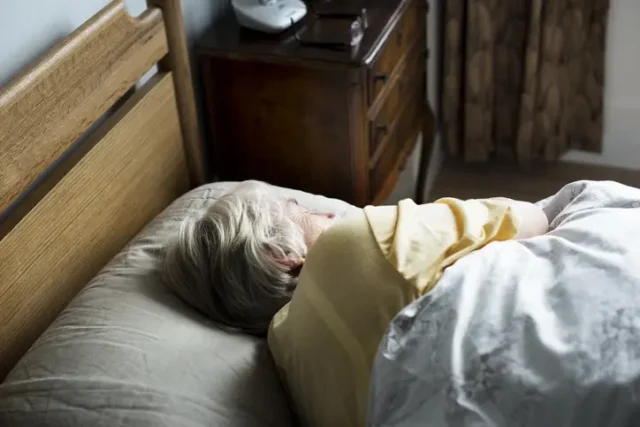 An old person laying down in bed suffering from nursing home sexual abuse.