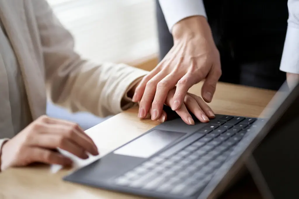 A worker placing their hand on top of another person's hand, suggesting quid pro quo harassment in the workplace.