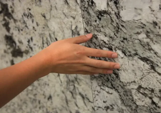 A hand touching a granite wall