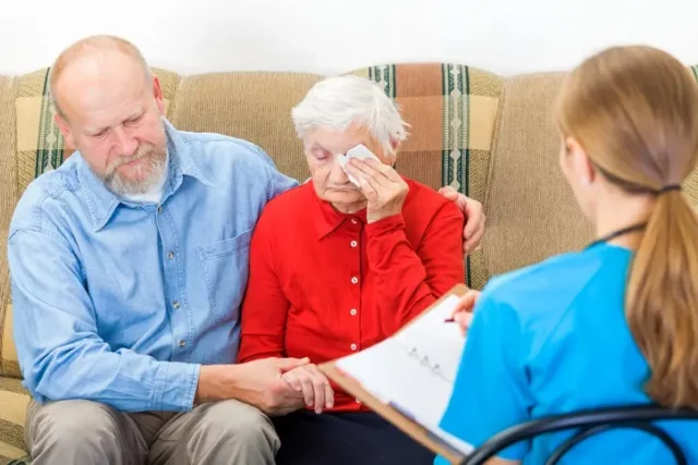 An older woman reporting nursing home abuse to a nurse.