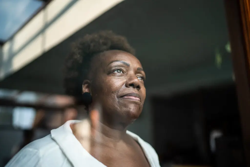 A woman looking out of a window, suffering nursing home abuse in Utah.