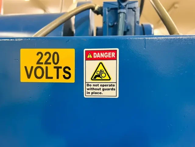 A danger sign by a heavy machine warning of industrial injury.