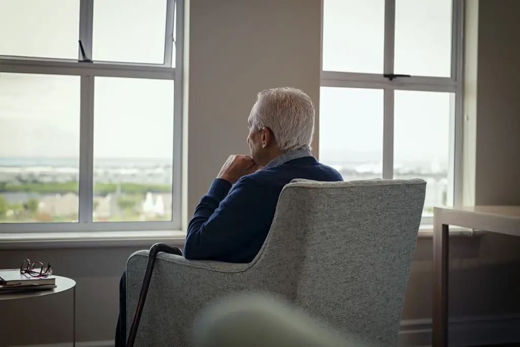 An elderly man looking out of a window, suffering through nursing home abuse in Wyoming.