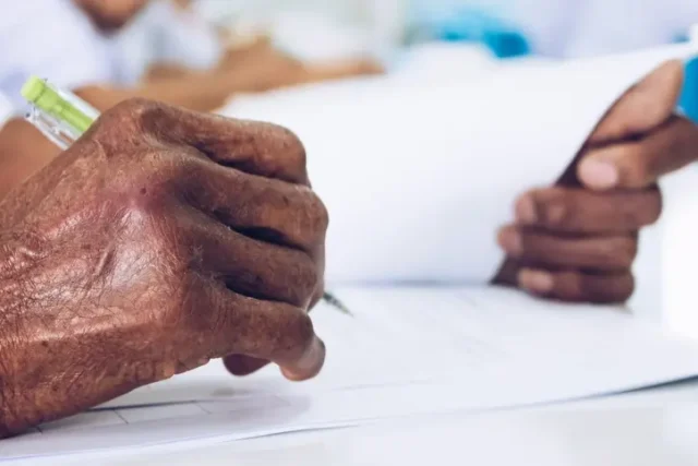 An old person writing on a piece of paper.