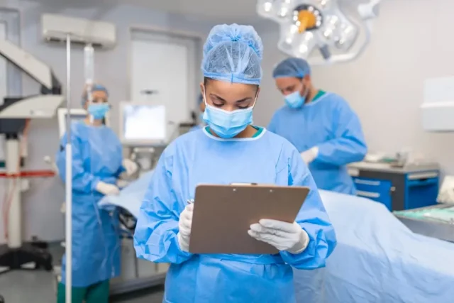 A surgeon filling out information on a clipboard, wondering if surgery increased their workers' comp settlement.