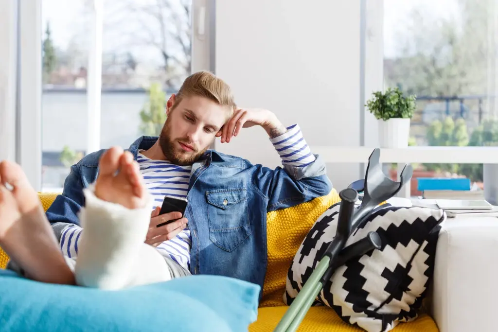 A man on the couch wondering how long does his workers' comp last.