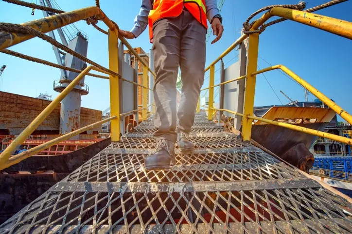 A maritime worker walking down a ramp.