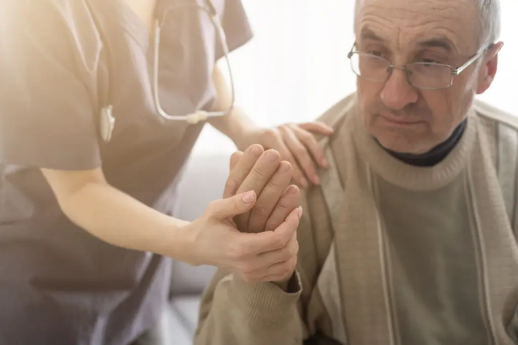 An old man suffering memory loss after a car accident. He is holding a nurse's hand.