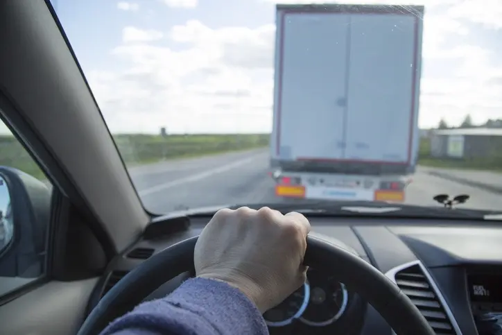 someone-driving-behind-a-truck Driver behind a semi-truck on the road.